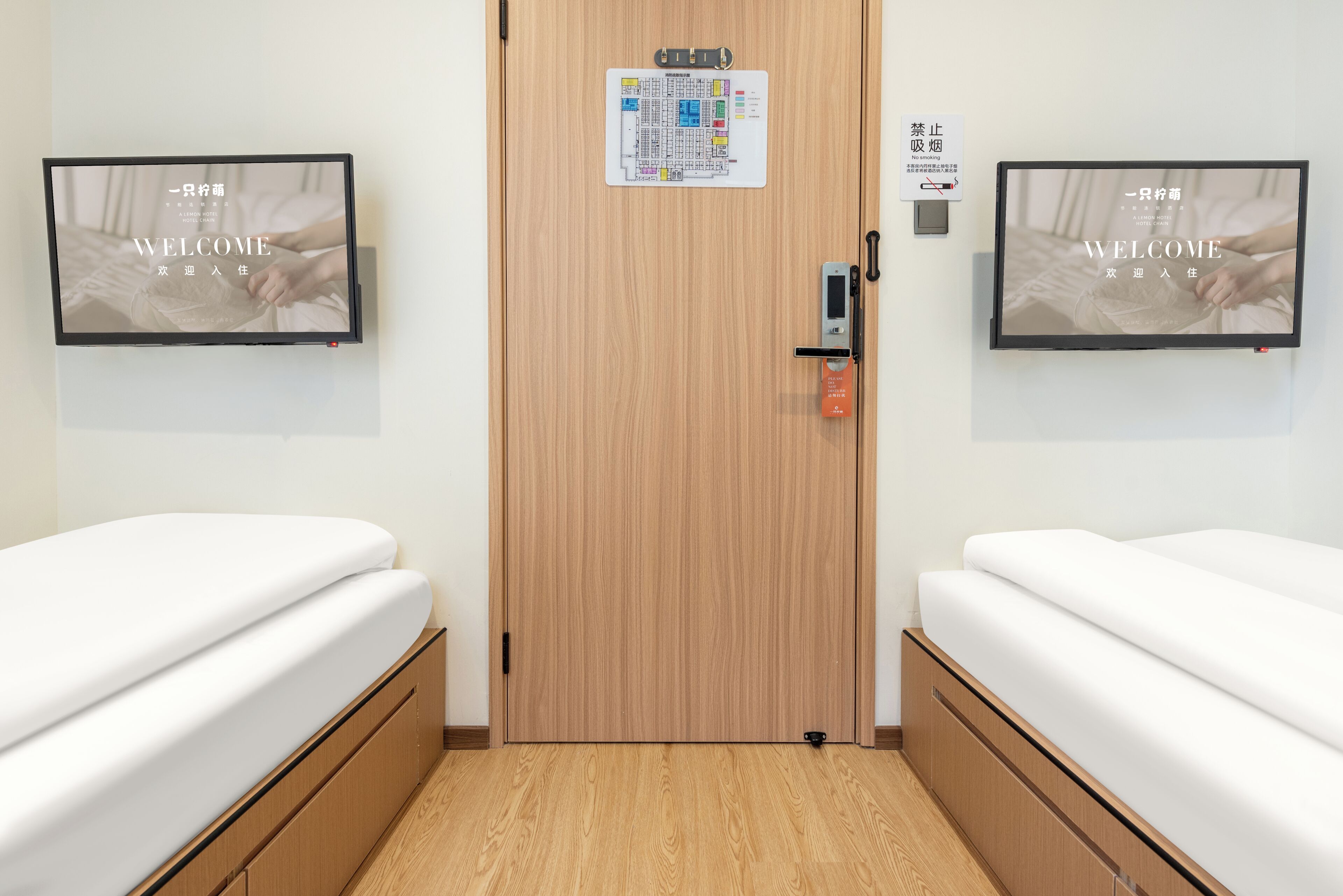 A hotel room with two beds, a wooden door, a map on the wall, and a no-smoking sign.