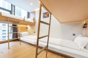 Una habitación de hotel moderna con una cama litera, una escalera de madera, un sofá y vistas a la ciudad.
