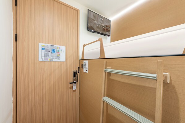 Ein Hotelzimmer mit Holztür, einem an der Wand befestigten Fernseher und einem Bett mit einem Holz Kopfteil.