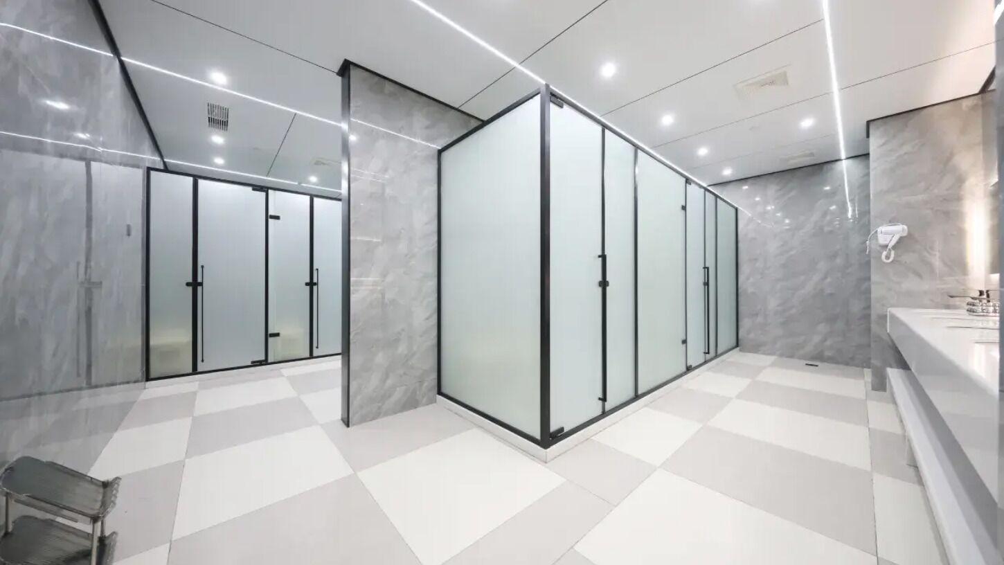 Un interno moderno con pavimento a scacchi, pareti divisorie in vetro e una parete in marmo.