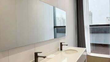 Un baño moderno con dos lavabos, un espejo grande y vistas de la ciudad a través de una ventana.