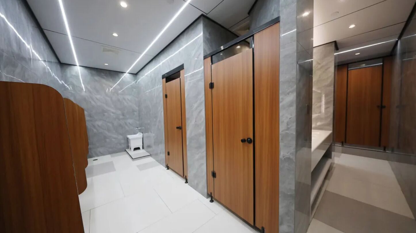A modern bathroom with wooden cabinets, a white toilet, and a marble wall.