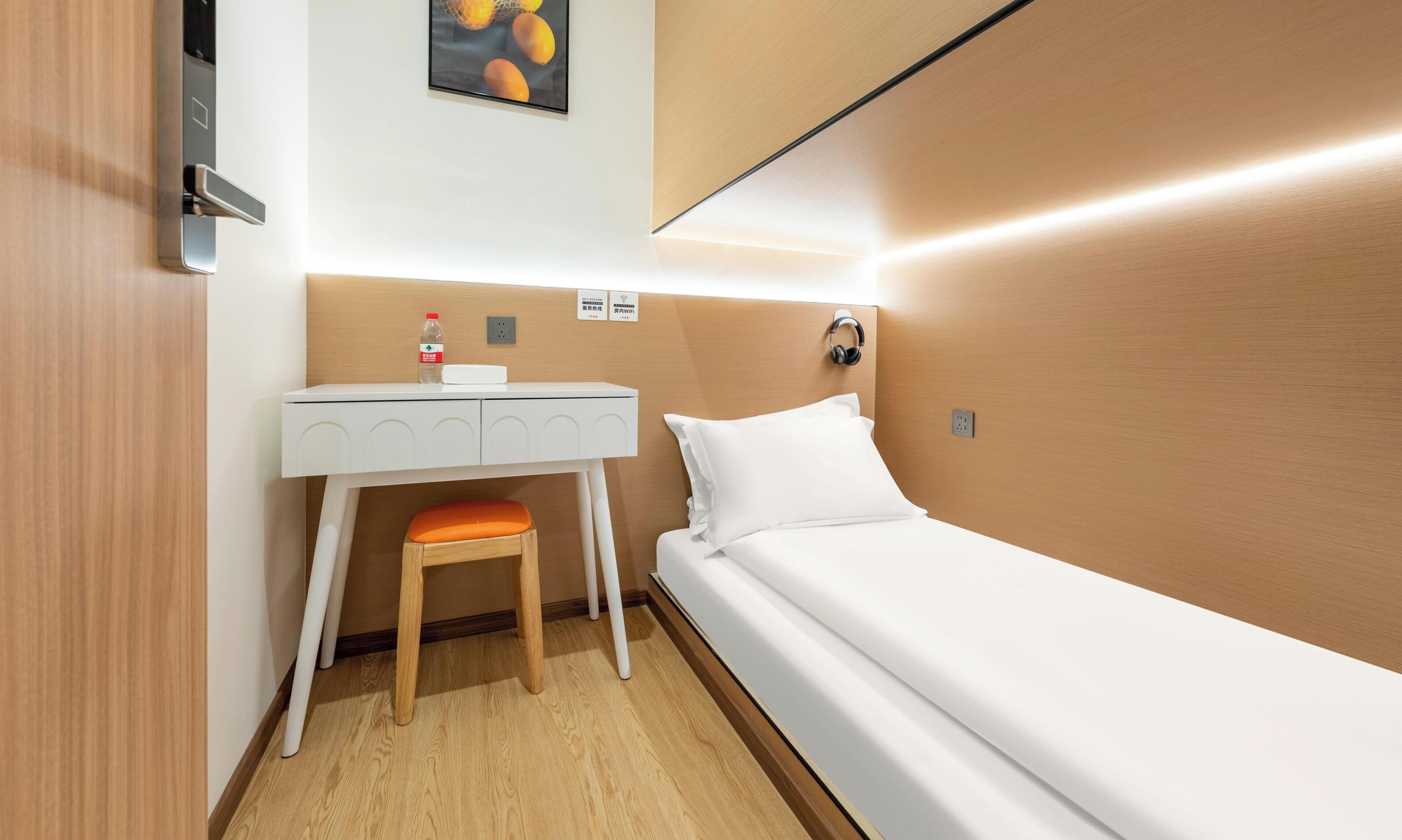 Ein kleines Hotelzimmer mit Bett, Schreibtisch und Stuhl.