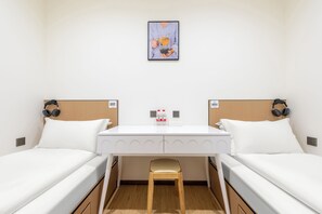 A hotel room with two single beds, a small desk, a chair, and a wall-mounted painting. - Lemon Hotel-Hangzhou West Lake (Hangzhou)