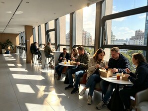 Un espace intérieur moderne, doté de grandes fenêtres, d’un mobilier confortable et offrant une vue sur le paysage urbain.
