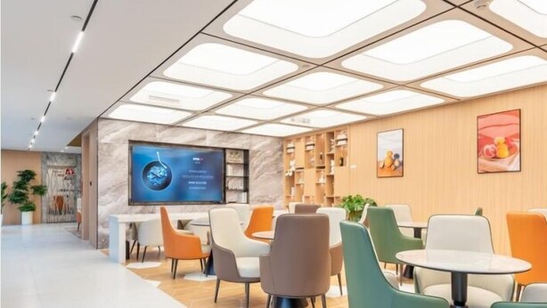 Ein modernes Interieur mit einer Rezeption, einer Sitzecke und einem großen Bildschirm.