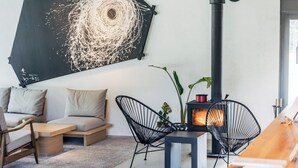 A modern living room with a sofa, two black wireframe chairs, a wooden coffee table, and a fireplace. - Auberge eaufeu (Komatsu)