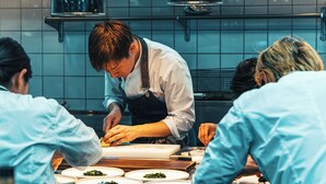 A chef preparing food in a kitchen with tiled walls and stainless steel appliances. - Auberge eaufeu (Komatsu)