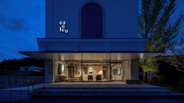 A modern building with a large arched entrance and a visible interior with seating and a kitchen area. - Auberge eaufeu (Komatsu)