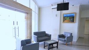A modern living room with two grey armchairs, a glass coffee table, and a painting on the wall. - Nusantara Rooms Mahakam By Reccoma (Cikarang)