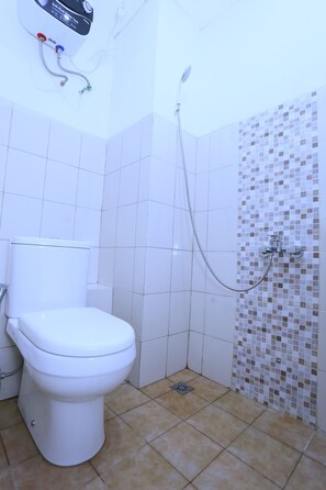 A bathroom with a toilet, a shower, and a tiled wall. - Nusantara Rooms Mahakam By Reccoma (Cikarang)