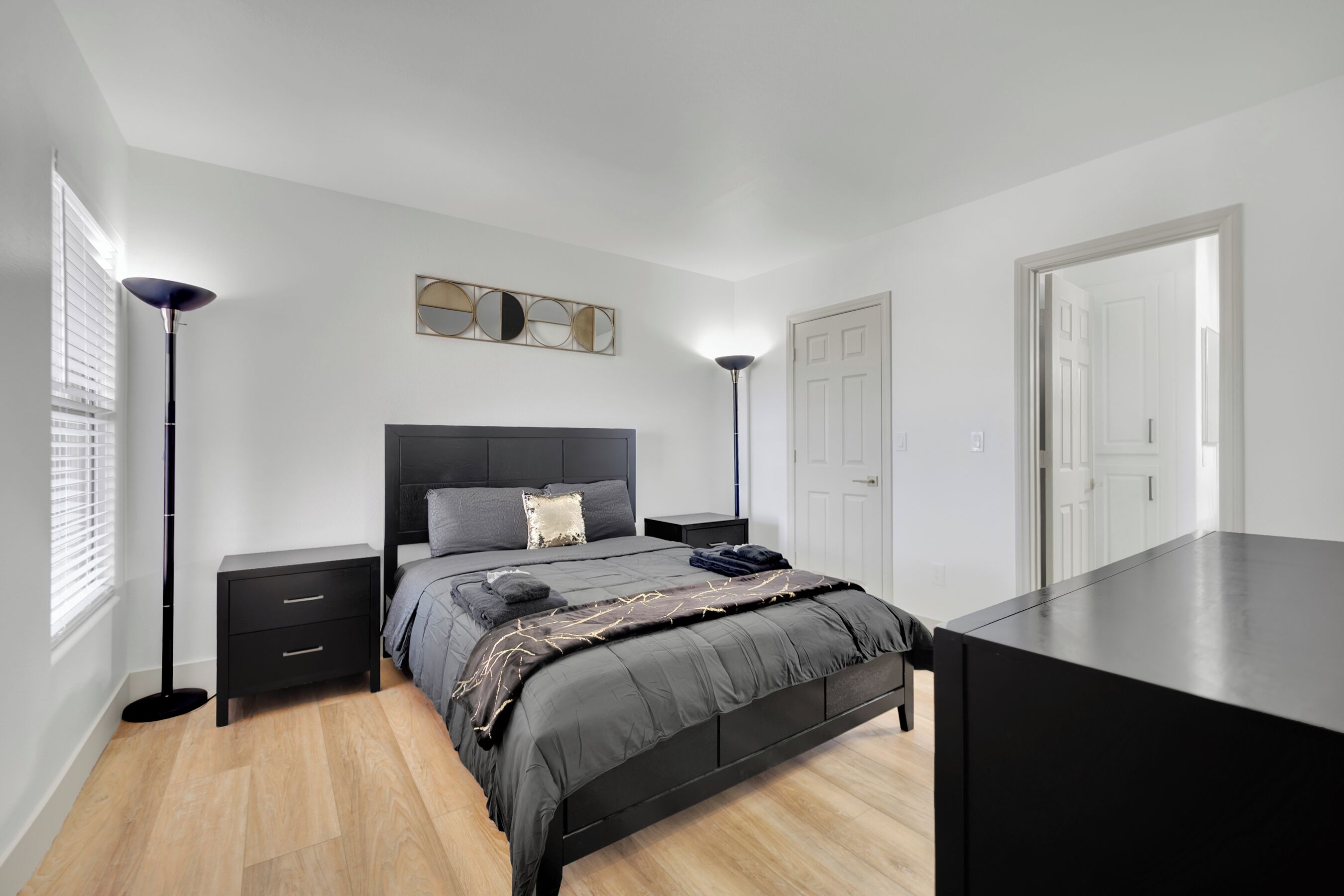 Quarto moderno com uma cama grande, mesas de cabeceira, uma escrivaninha e um espelho.