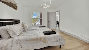 A modern bedroom with a large bed, a window with a view, and a minimalist design. - Charming 2-bedroom condo near to Strip (Las Vegas)