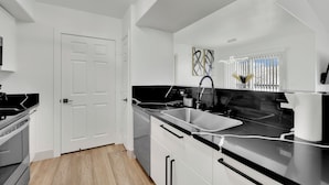A modern kitchen with white cabinets, a black countertop, and a stainless steel sink. - Charming 2-bedroom condo near to Strip (Las Vegas)