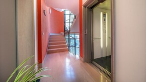 A modern interior with a staircase, a glass railing, and a door leading to an elevator. - GuestHost - Cozy 38 sqm apartment for 2 people, located near the Porta di Aquileia in Udine. It features a reserved covered parking space for guests, offering comfort and convenience. The area is rich in history and charm, just steps away from Udine's hi (Udine)