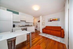 Une cuisine moderne avec des meubles blancs, une table à manger avec des chaises et un plancher en bois.