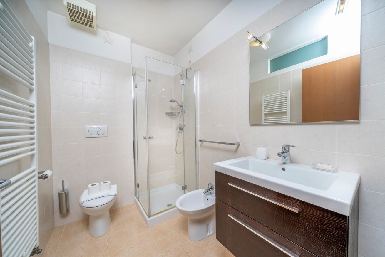 A modern bathroom with a glass shower enclosure, a white sink, and a mirror above it.