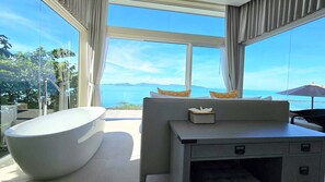 Un bagno moderno con una vasca da bagno freestanding, un mobile lavabo con specchio e vista sul mare.