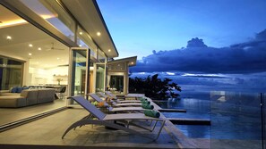 Una casa moderna con veranda vetrata, zona pranzo e piscina.