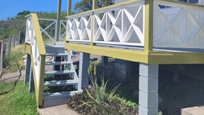 Un portico coperto con ringhiera bianca e dettagli gialli, che conduce a un edificio con diverse finestre.