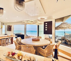 A spacious dining area with a large round table, wicker chairs, and a view of the ocean. - Magical OceanFront home in Capistrano Beach. All the comforts of home and more! (Dana Point)