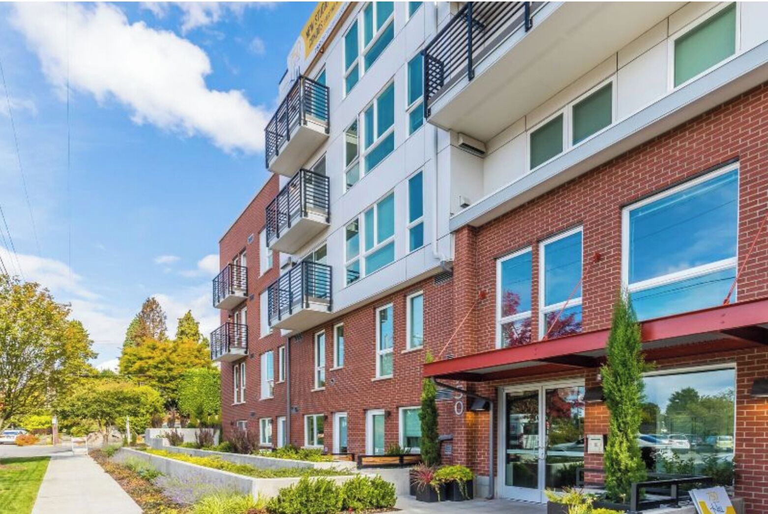 A multi-story residential building with balconies, large windows, and a brick facade.