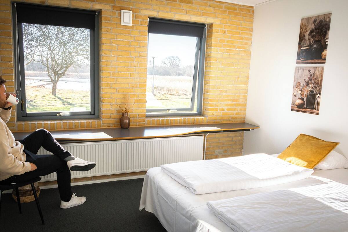 A room with a bed, a window with a view of a tree, and a radiator.