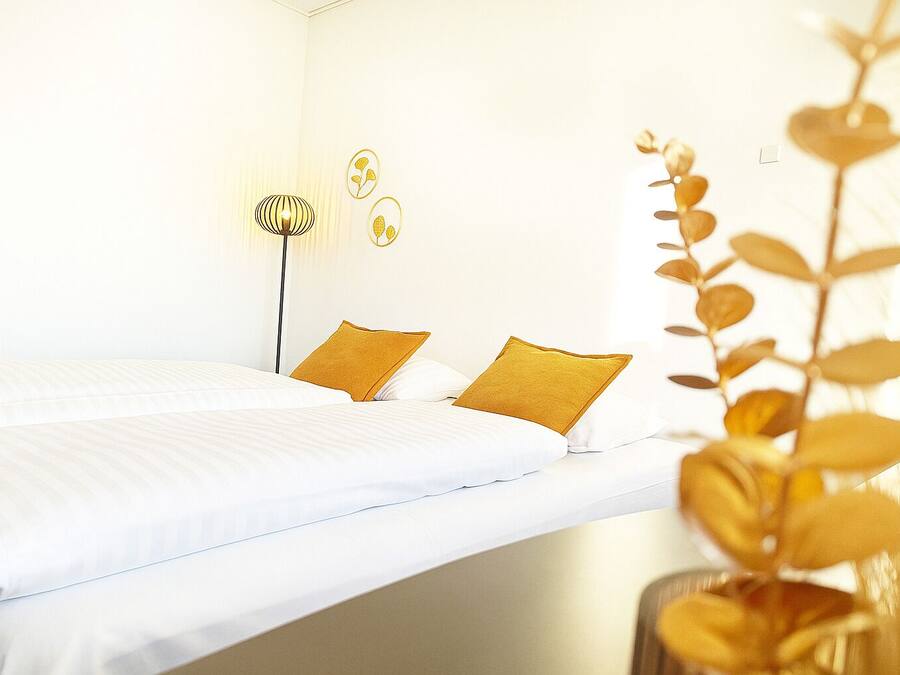 Une chambre d’hôtel avec un lit, deux oreillers, une lampe de chevet et des œuvres d’art murales.
