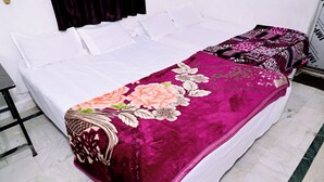 A bed with white bedding and a floral-patterned blanket. - SHIVAY GUEST HOUSE (Deoghar)