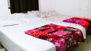 A room with two beds, one with a white bedspread and the other with a red and pink patterned bedspread. - SHIVAY GUEST HOUSE (Deoghar)