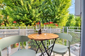 A table with two chairs on a balcony, a bottle of wine, and a glass on the table.