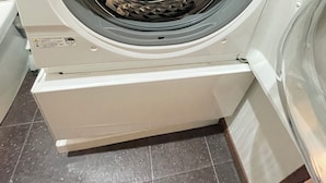 Vue de face d’un lave-linge blanc, doté d’une porte circulaire et d’un panneau de commande situé sur le côté gauche.