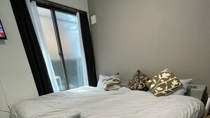 Une chambre d’hôtel moderne avec un grand lit, deux serviettes, une fenêtre avec des rideaux et une table de chevet.