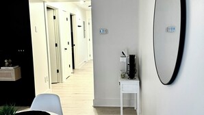 A modern interior with a dining area featuring a round table and white chairs, a small white side table, and a large mirror on the wall.