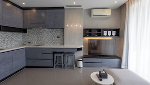 A modern kitchen with grey cabinetry, a tiled backsplash, and a built-in island with stools. - 600m to beach New City gate P214 c60 (Kamala)