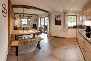 A modern kitchen with a dining area, wooden beams, and a large window.