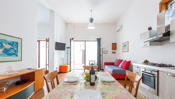 A modern kitchen with a dining area set for two, featuring a table with plates, cutlery, and a bottle.