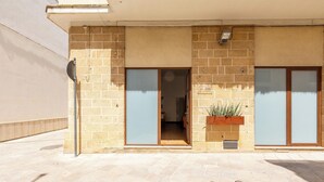 A building with a brick facade, large sliding glass doors, and a potted plant on the ground floor.