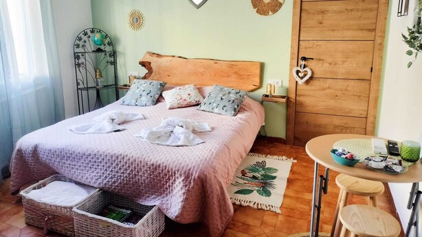 Ein ordentlich eingerichtetes Schlafzimmer mit einem Bett, Nachttischen, einem Holzschrank und einem kleinen runden Tisch mit Hockern.