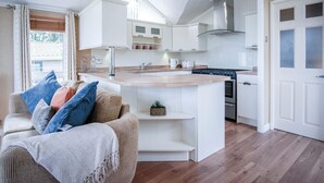 A modern kitchen with white cabinetry, a wooden countertop, and a built-in stove. - 3 Manor Lodge - 2 Bedroom Lodge - Pendine (Carmarthen)