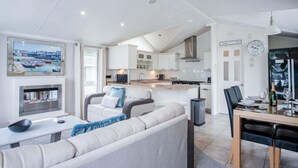 Een moderne keuken met witte kastjes, een roestvrijstalen afzuigkap en een eethoek met een tafel en stoelen.