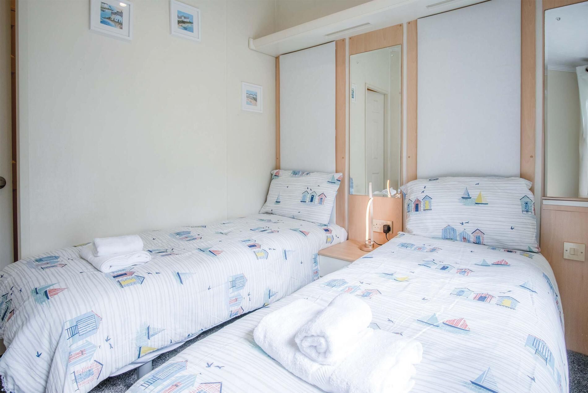Ein Doppelzimmer mit zwei Betten, einem Spiegel und einem Nachttisch.