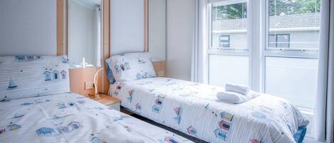 A hotel room with two beds, a large window, and a mirror.