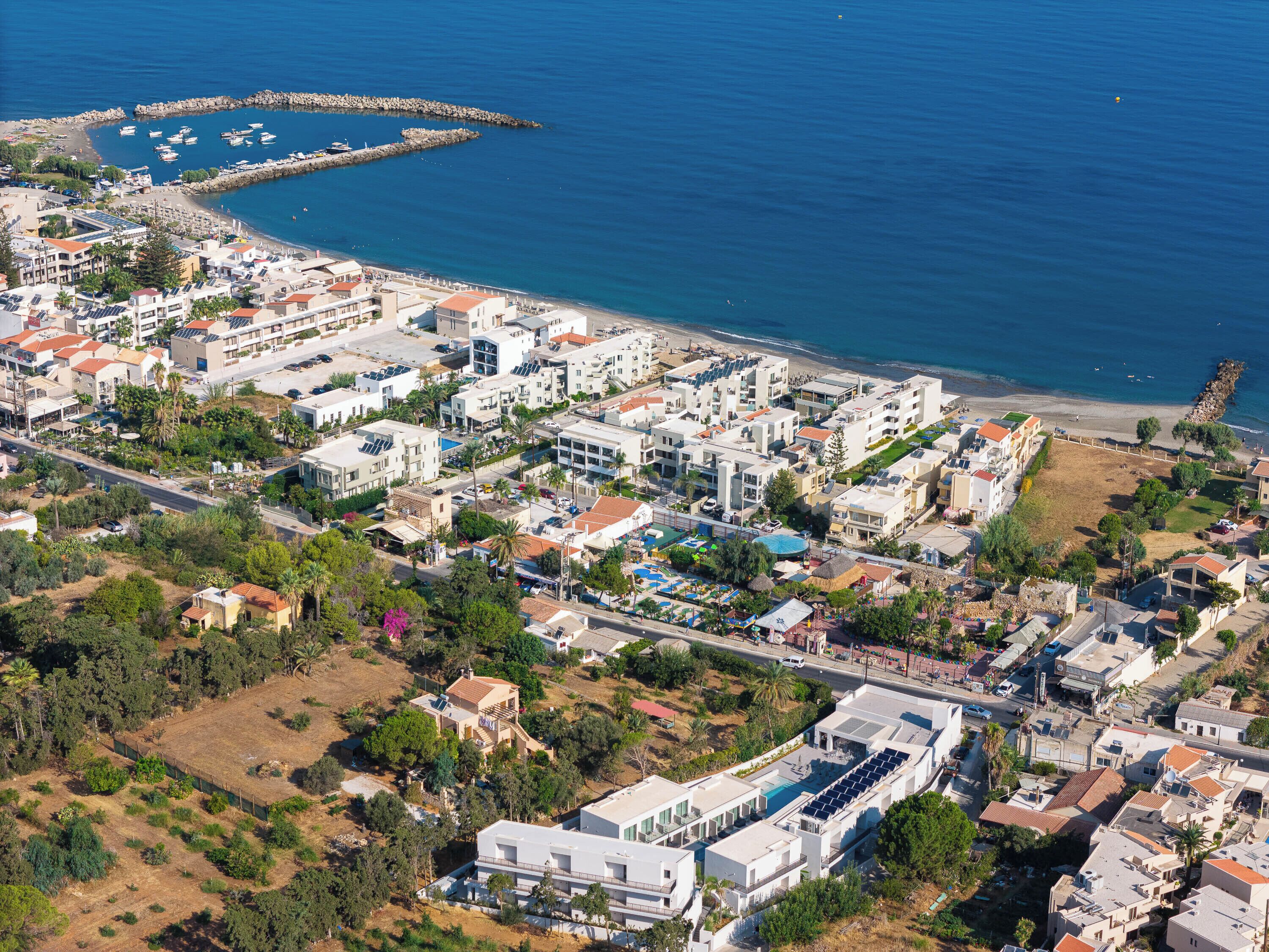 Vista aérea de una zona residencial costera con edificios modernos, un puerto deportivo y una playa.
