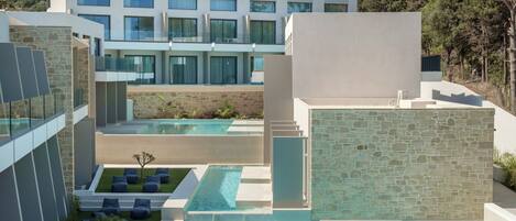 A modern hotel with a pool area, outdoor seating, and a view of the surrounding landscape.
