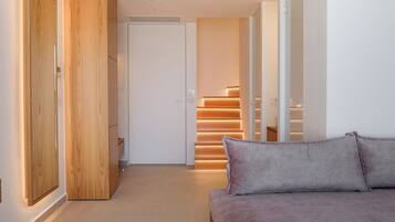 A modern interior with a sofa, wooden wardrobe, and a staircase leading to an upper level.