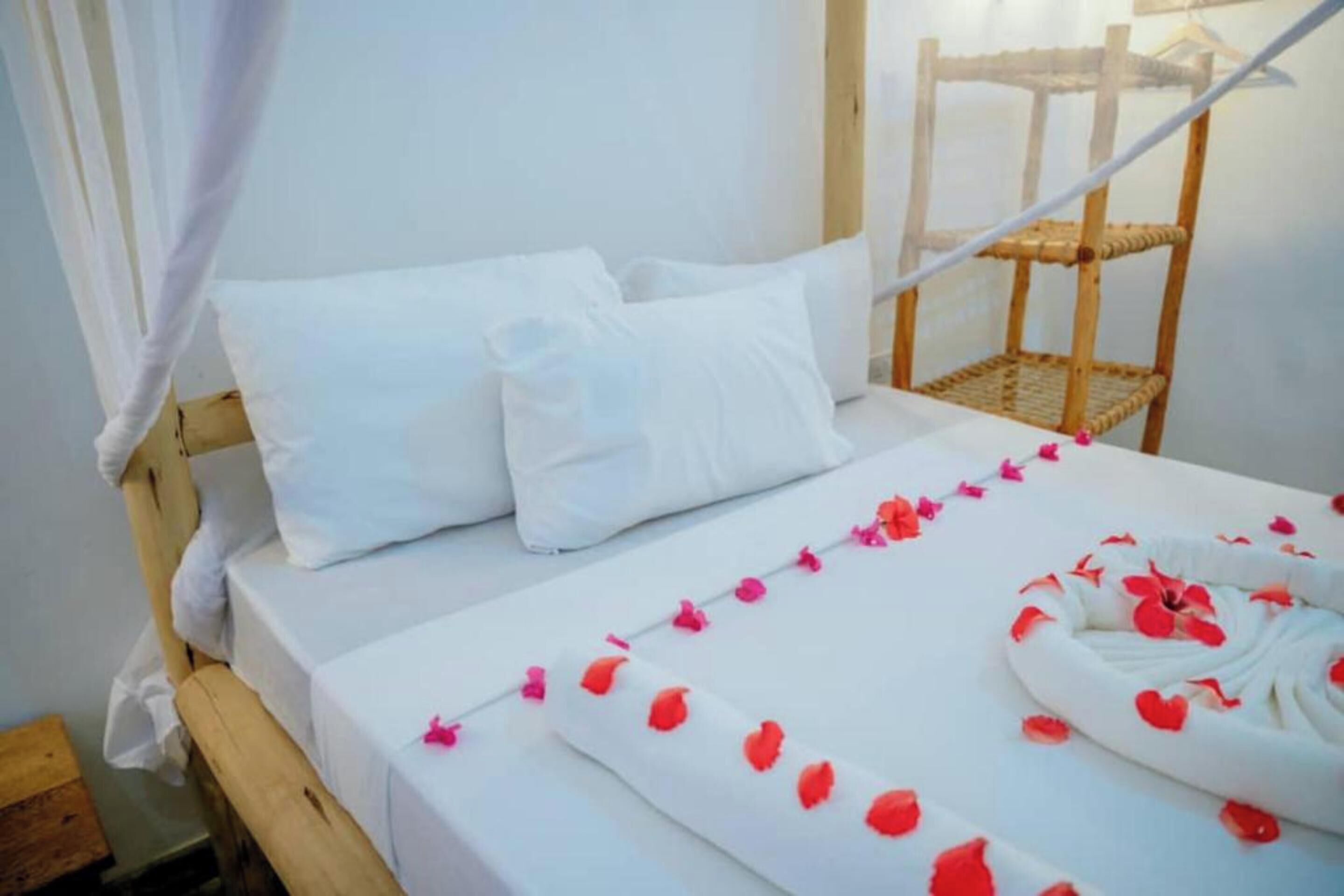 A bed with white bedding, a wooden headboard, and a woven chair.
