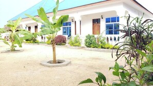 A building with a blue roof and white walls, surrounded by a garden with various plants. - Serenity Boutique Hotel (Jambiani)