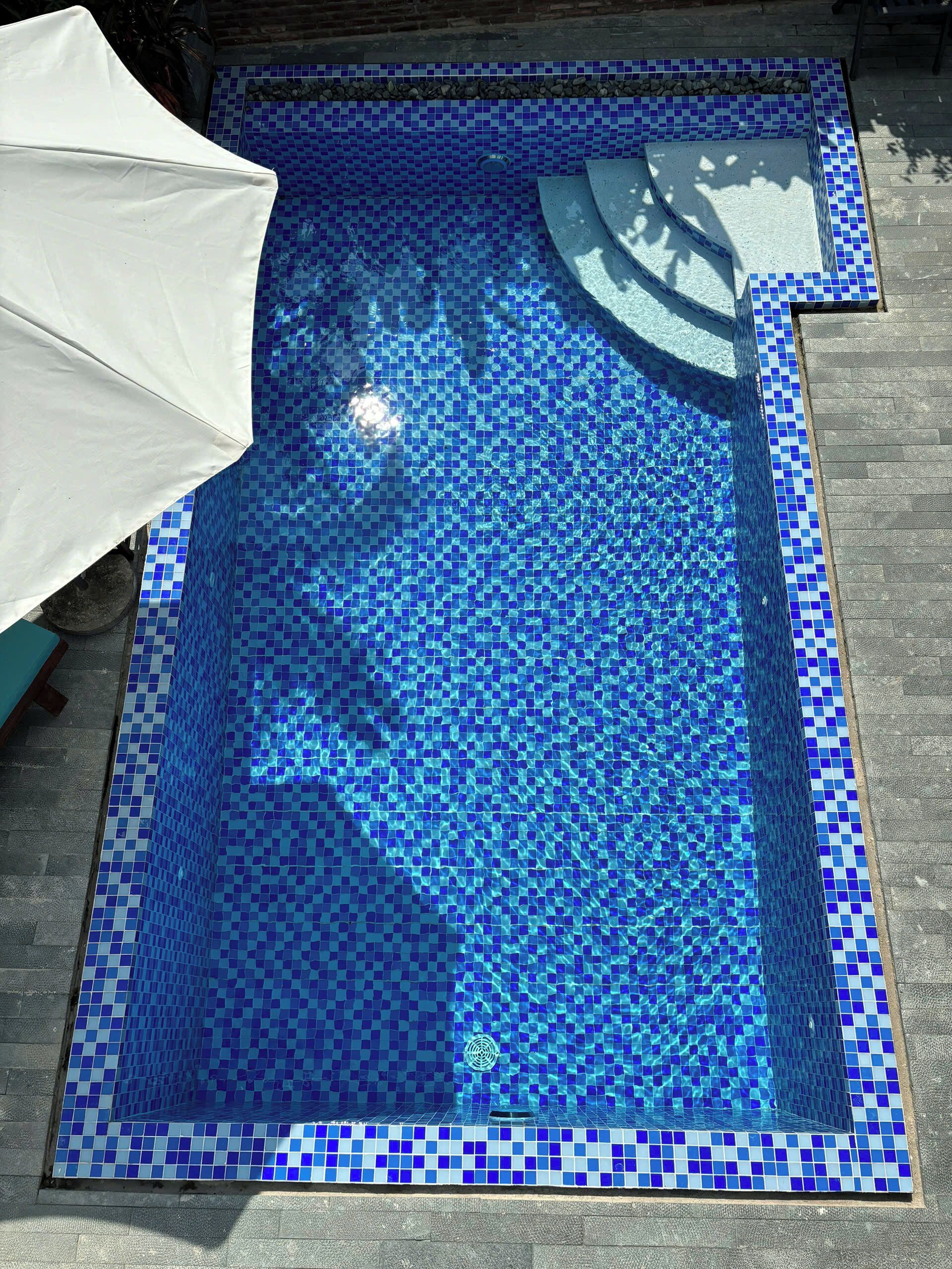 Una piscina con mosaicos azules y un borde de piedra.