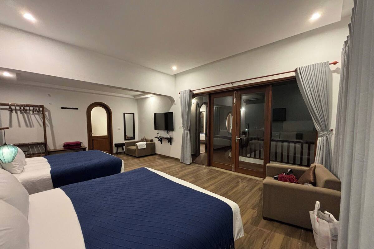 Une chambre d’hôtel avec deux lits, une télévision, un bureau et un balcon.